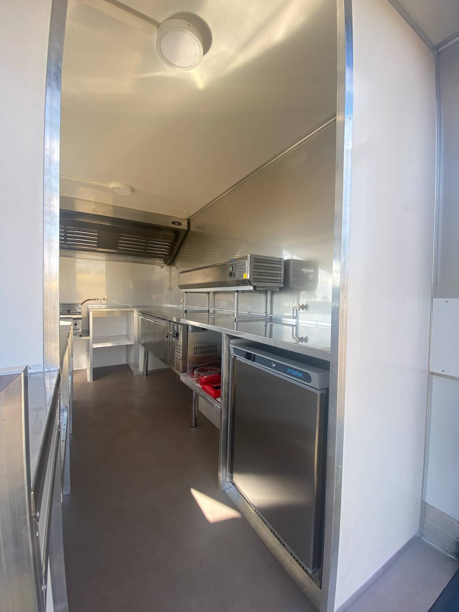 Intérieur food truck BBQ avec comptoir réfrigéré Polar, étagères inox, hotte et rangements professionnels