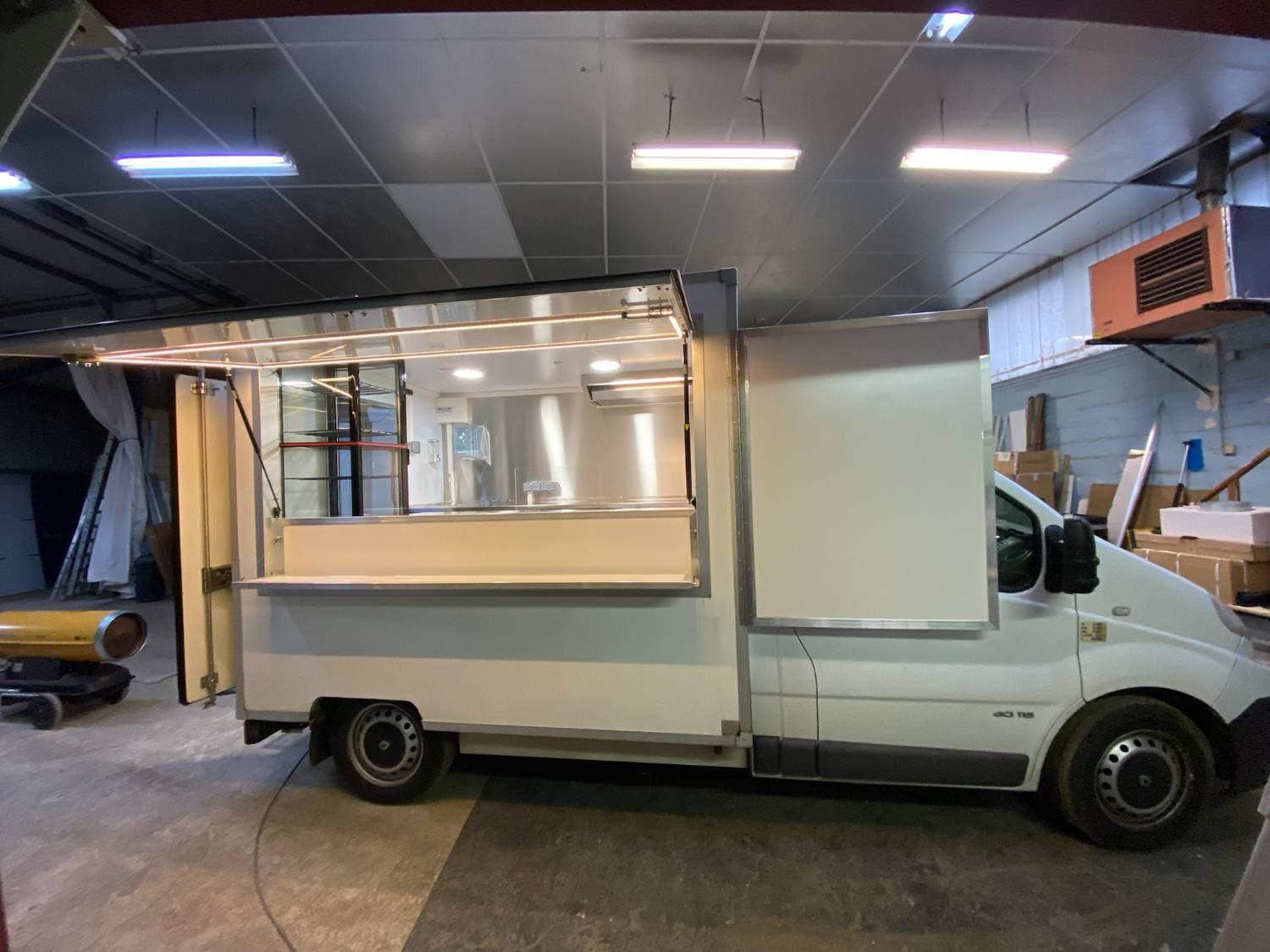 Intérieur camion crêpes avec plan de travail inox, évier, hotte aspirante, distributeur essuie-mains et rangements