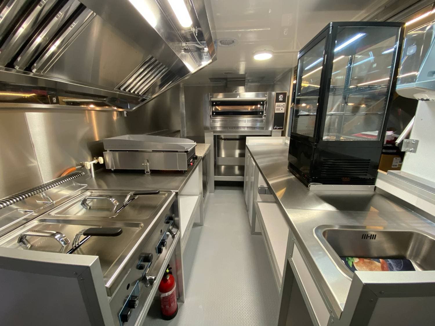 Cuisine intérieure camion pizza snack avec four à pizza, plancha, friteuse, vitrine réfrigérée et évier