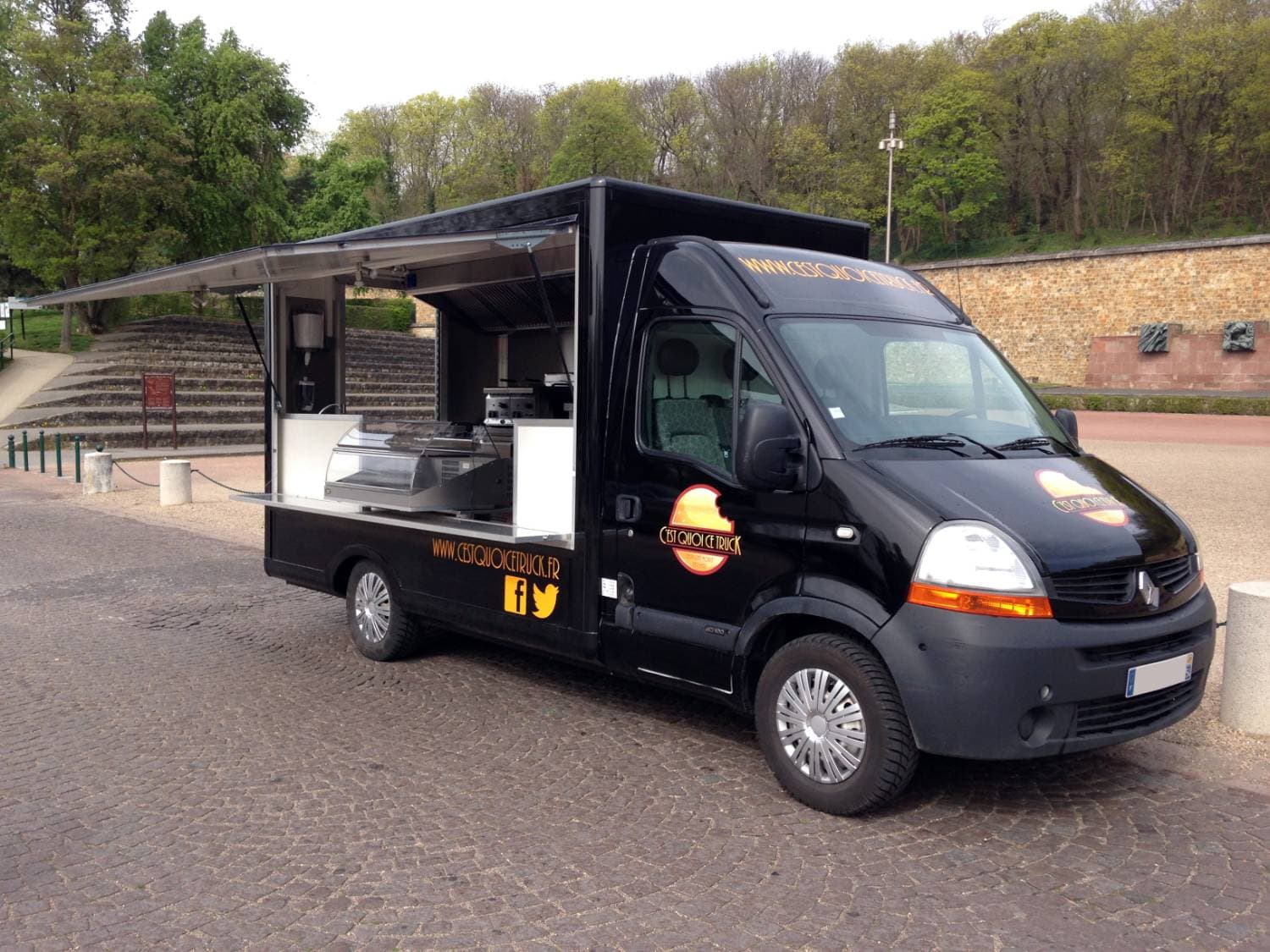 Food truck noir C'est Quoi Ce Truck vue trois-quarts avant avec volet ouvert et auvent déployé