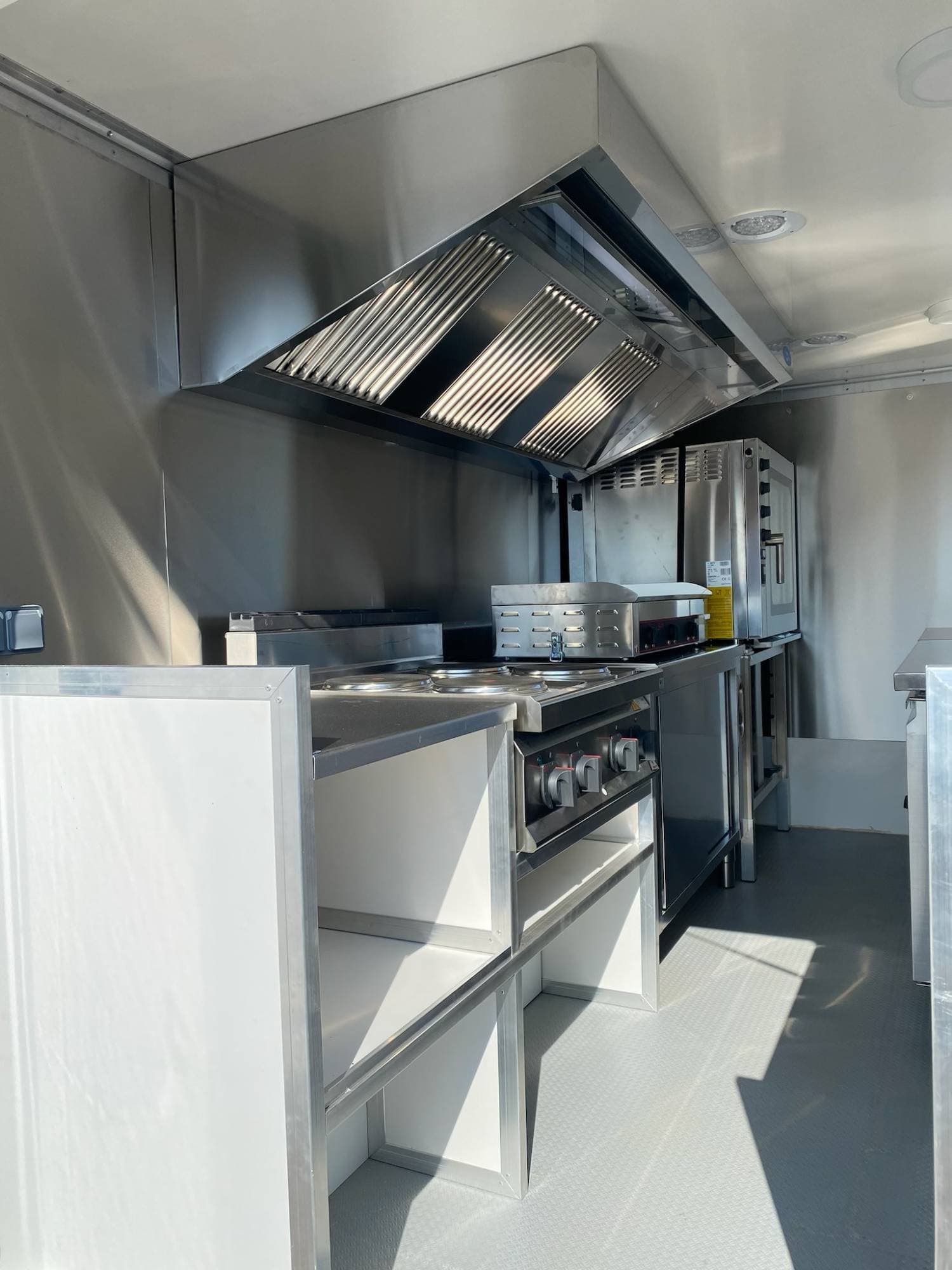 Arrière cuisine camion avec hotte aspirante, plancha, four à convection et étagères de rangement inox