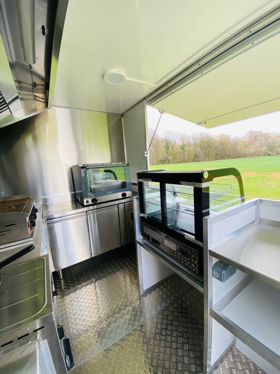 Intérieur côté service du food truck Tonton Burger avec four vitrine et vue sur la campagne