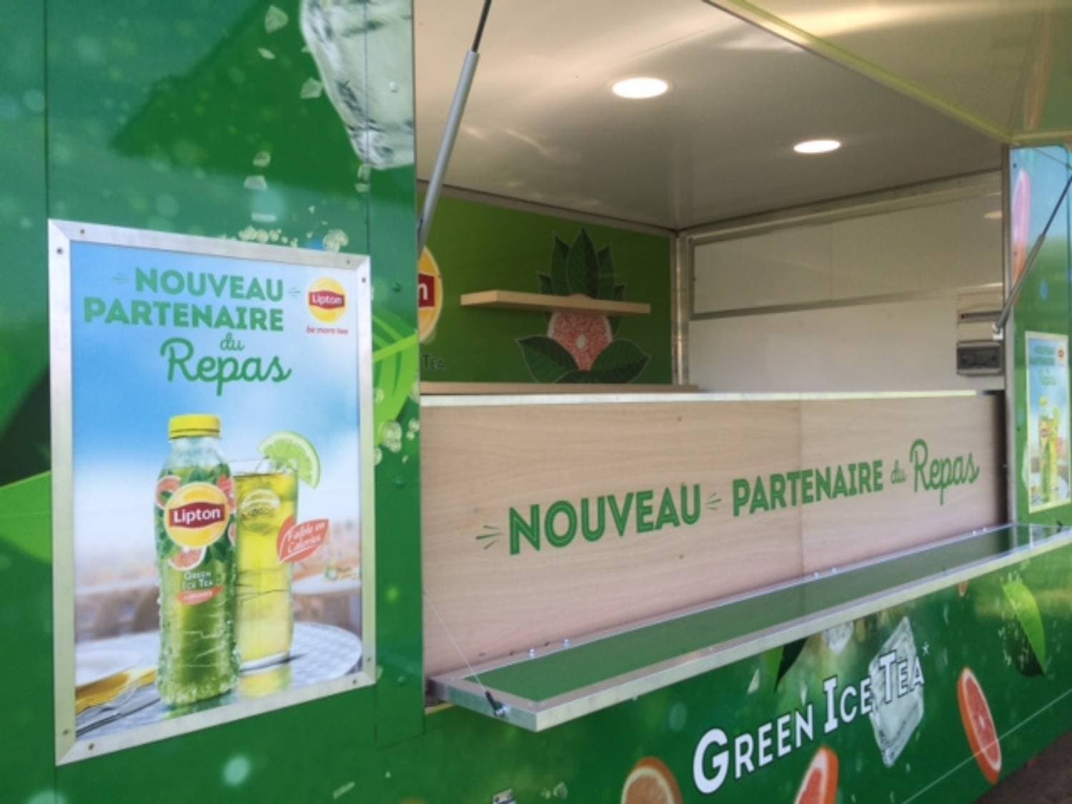 Détail comptoir ouvert du food truck Lipton Green Ice Tea avec affiche Nouveau Partenaire du Repas