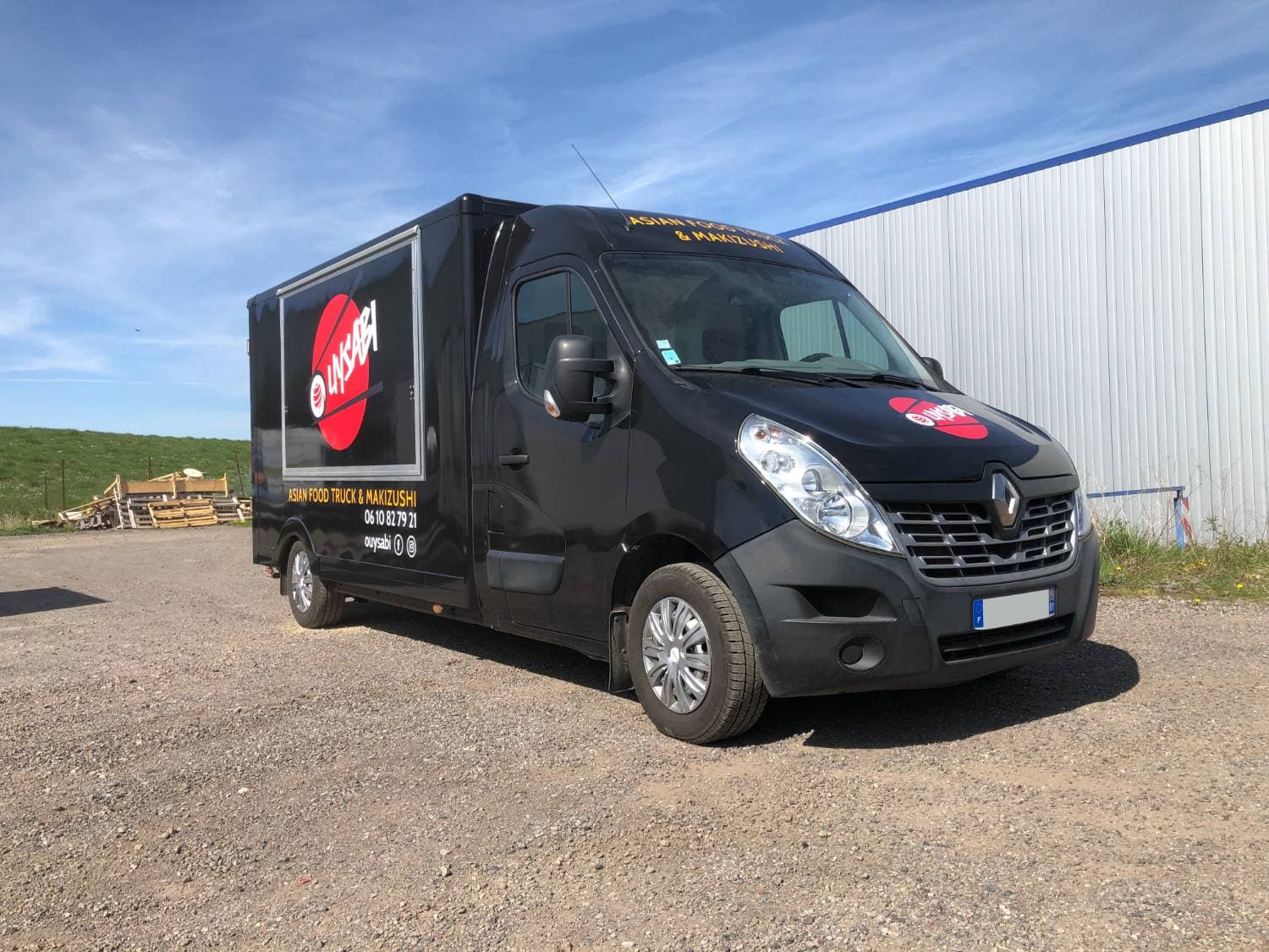 Renault Master noir Ouysabi Asian Food Truck vue trois-quarts avant sur terrain en gravier