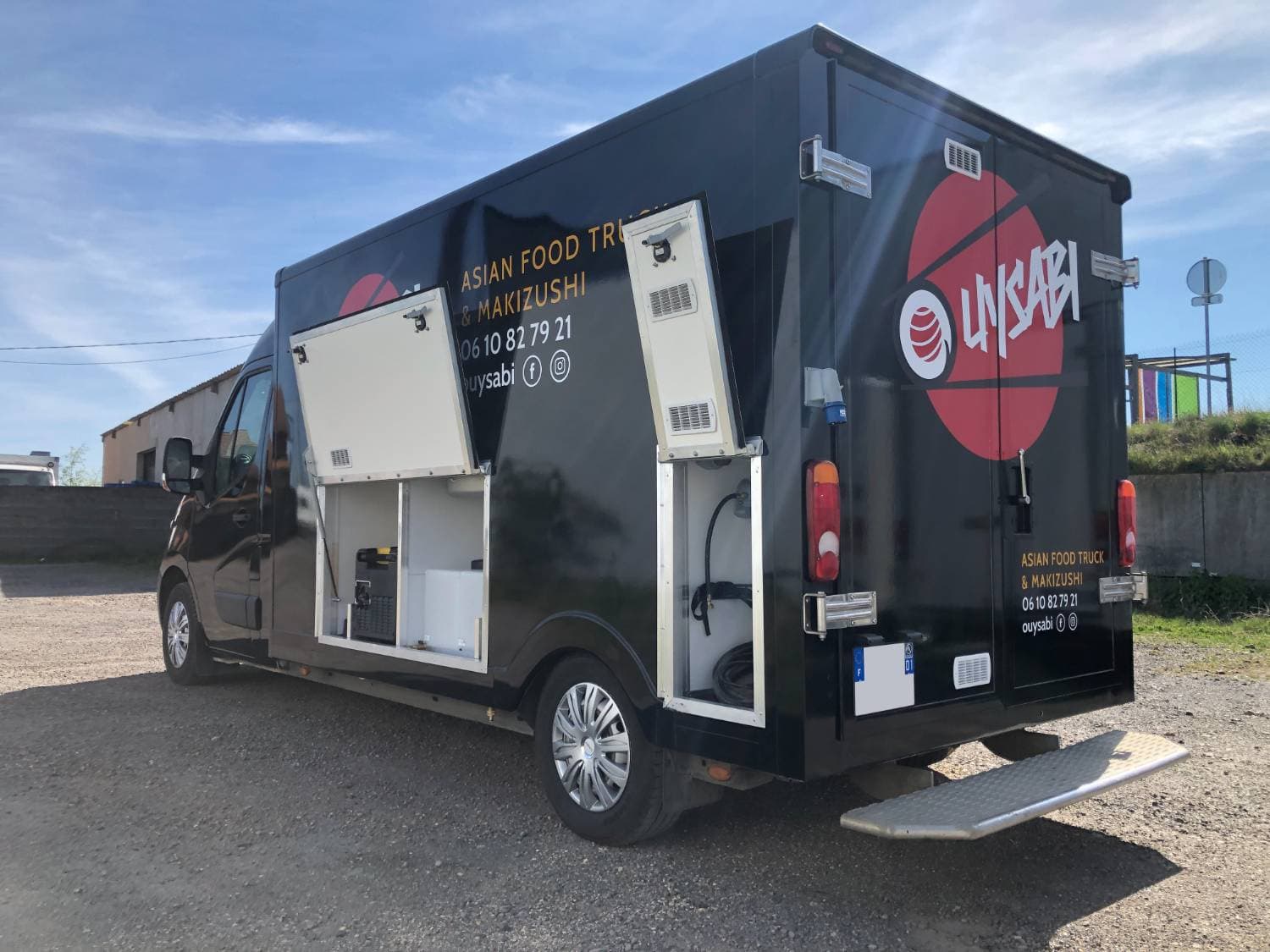Vue arrière du Renault Master noir Ouysabi avec logo sushi rouge, compartiments techniques ouverts