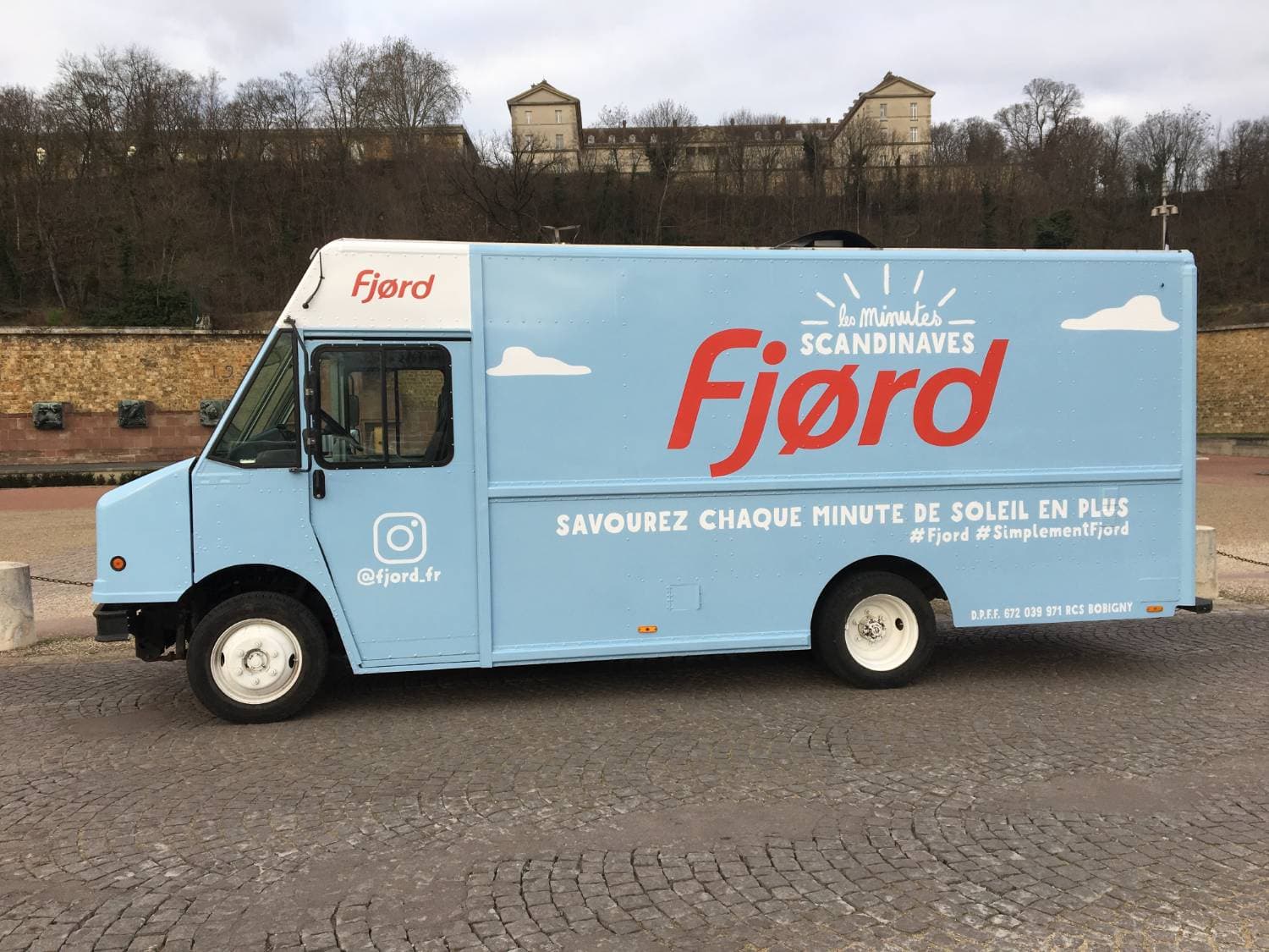 Vue latérale du Step Van bleu Fjord avec covering complet, nuages blancs et slogan scandinave