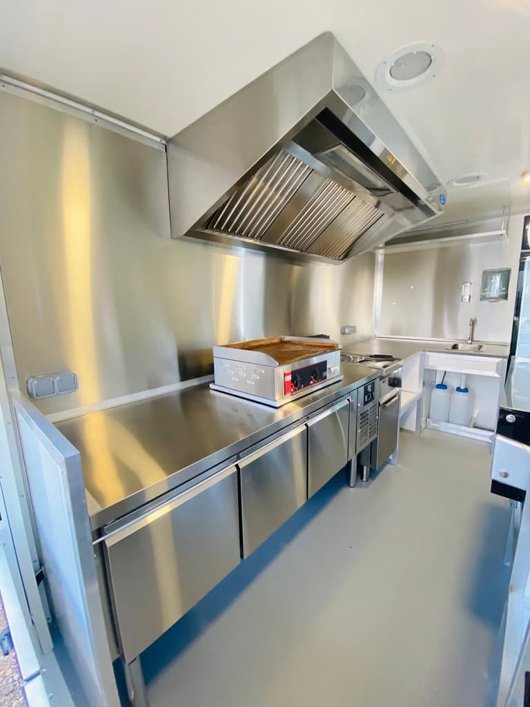 Intérieur cuisine professionnelle inox du food truck Air France avec plancha hotte et réfrigérateur