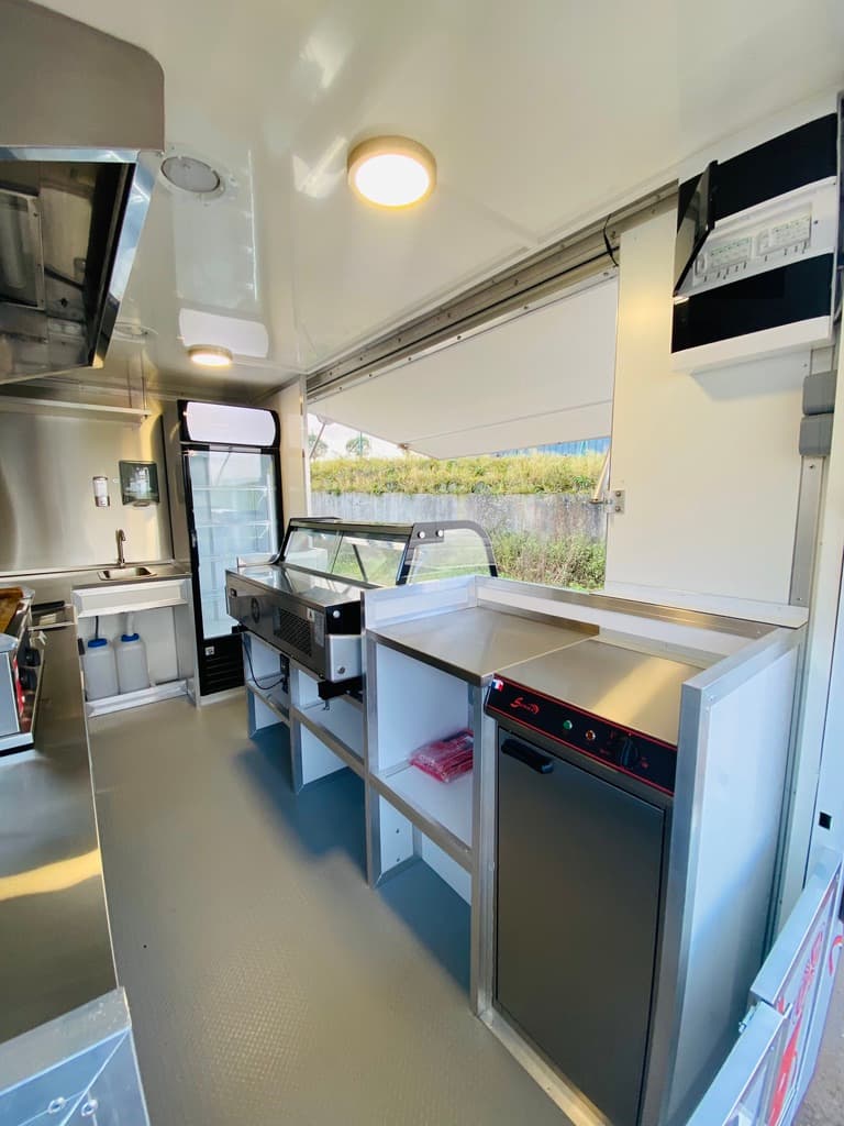 Intérieur côté comptoir du food truck Air France avec vitrine réfrigérée évier et volet de service ouvert