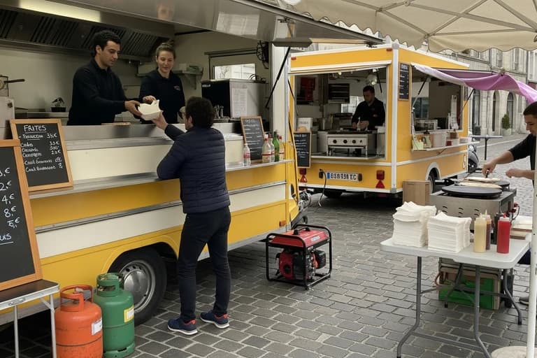 Deux remorques food truck jaunes en service : clients servis et crêpes préparées lors d'un événement de restauration ambulante.