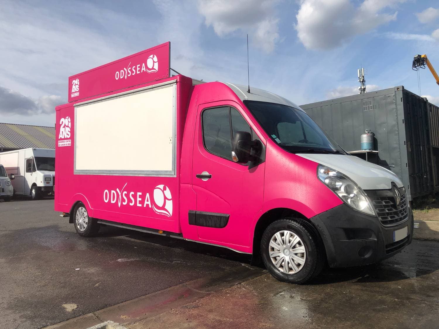 Renault Master rose Odyssea avec covering partiel 20 ans Ensemble contre le cancer du sein, vue trois-quarts avant sur parking