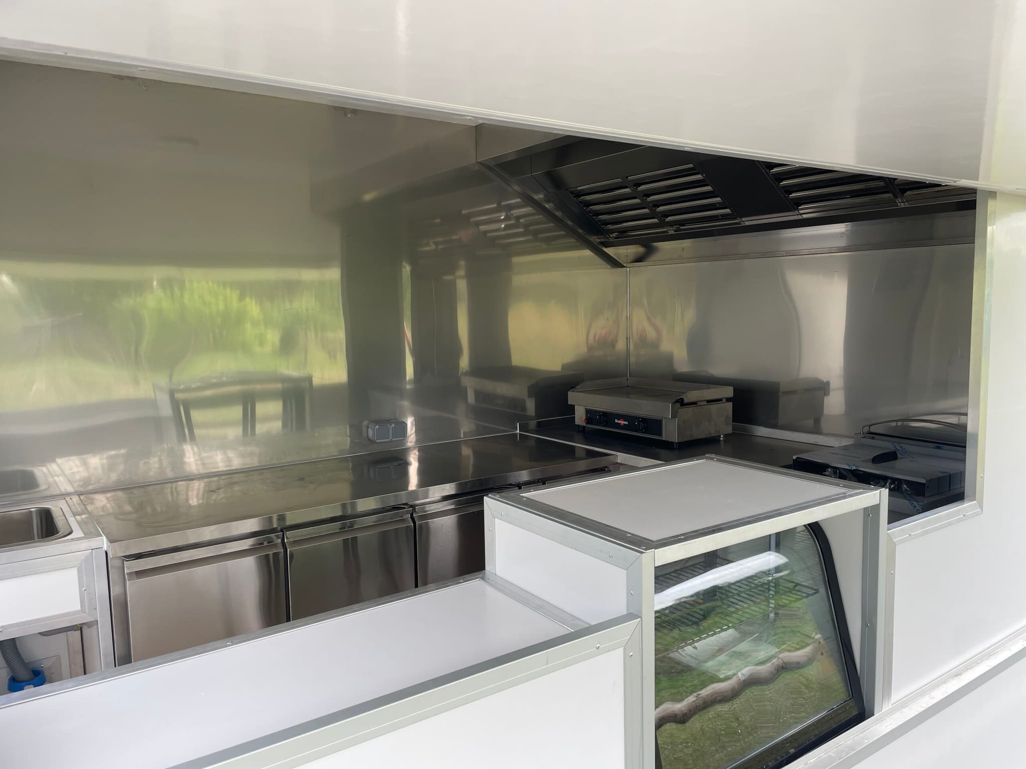 Aménagement intérieur inox — plancha, vitrine réfrigérée, réfrigérateur sous plan et hotte d'extraction