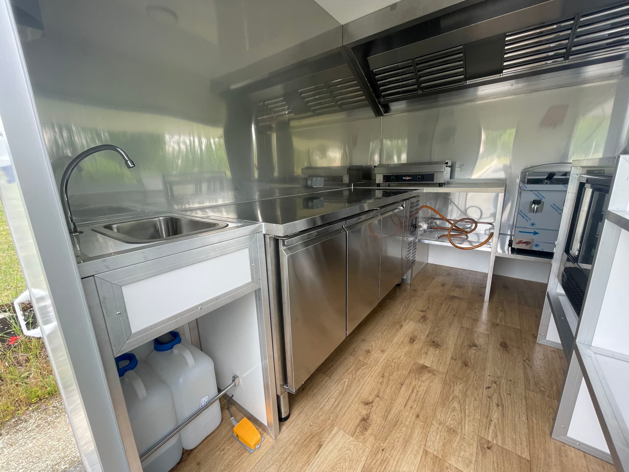 Vue intérieure complète — plonge, plan de travail inox, plancha, froid et machine à café, sol parquet