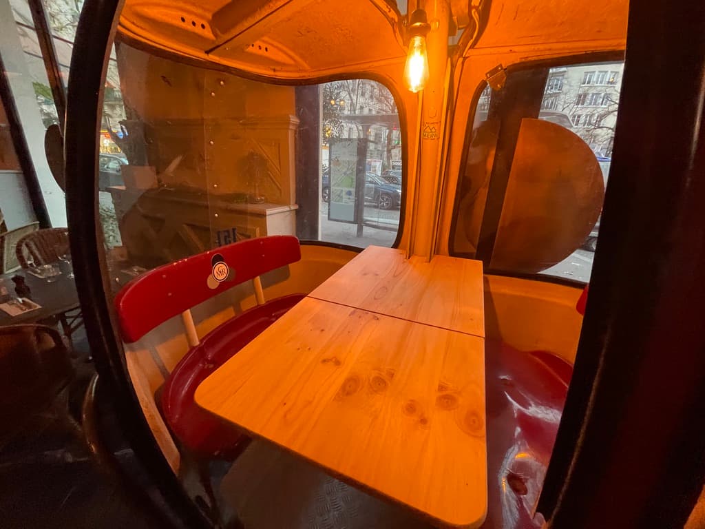 Intérieur de la télécabine — table en bois massif, banquettes rouges et éclairage Edison