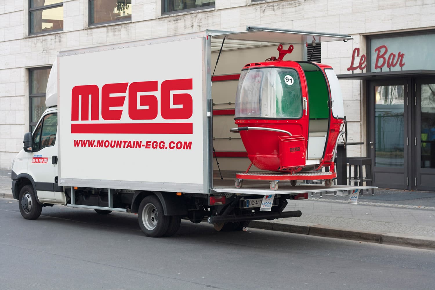 Livraison d'une télécabine MEGG rouge par camion — transport clé en main