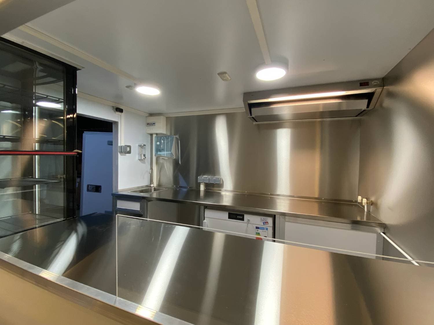 Camion crêpes blanc ouvert en atelier avec comptoir de service éclairé, vitrine et aménagement intérieur visible