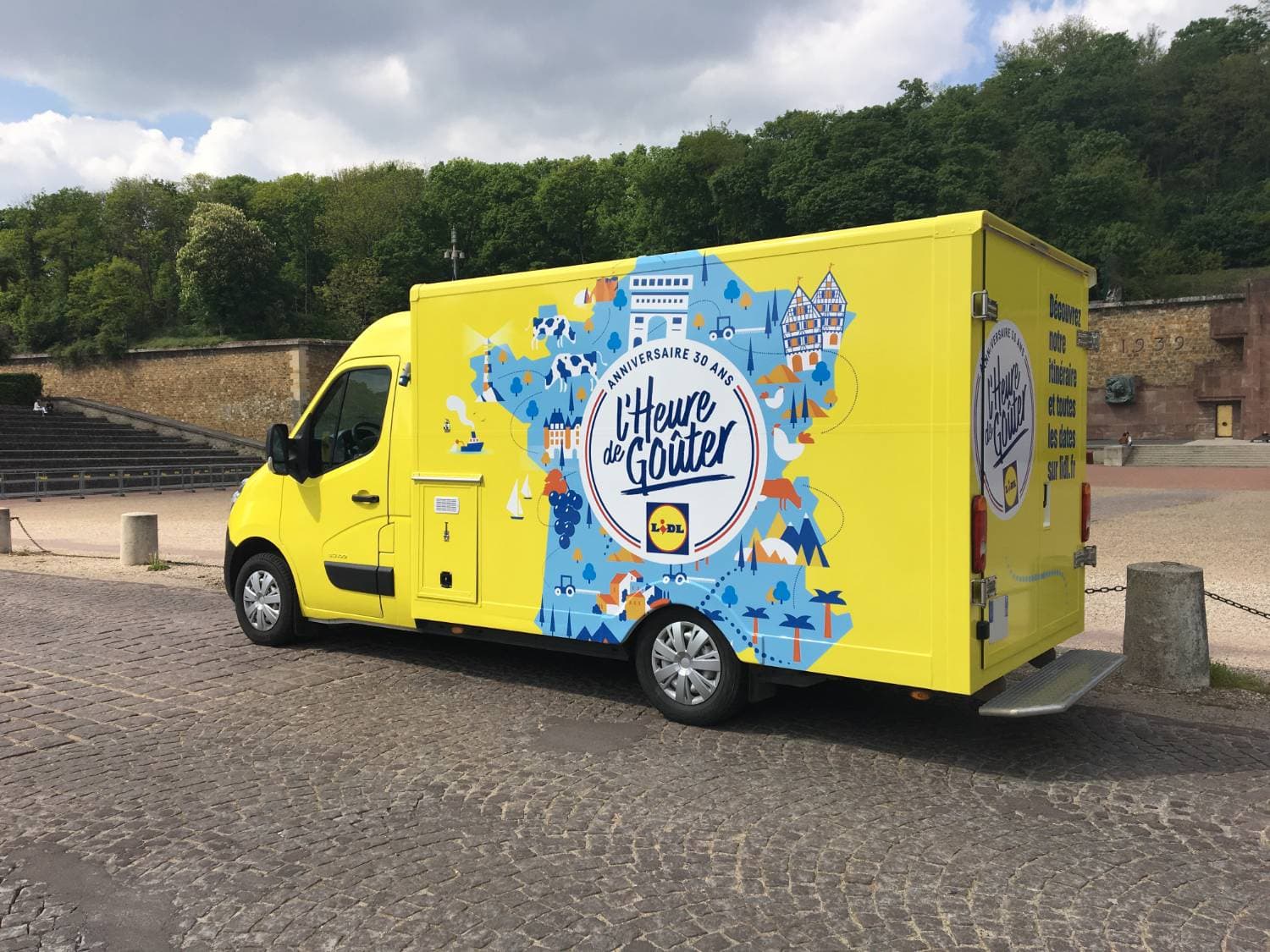 Renault Master Lidl jaune vif L'Heure de Goûter anniversaire 30 ans avec illustrations colorées sur esplanade