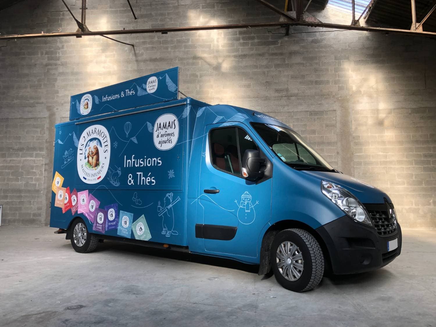 Renault Master Les 2 Marmottes bleu avec covering infusions et thés dans un entrepôt