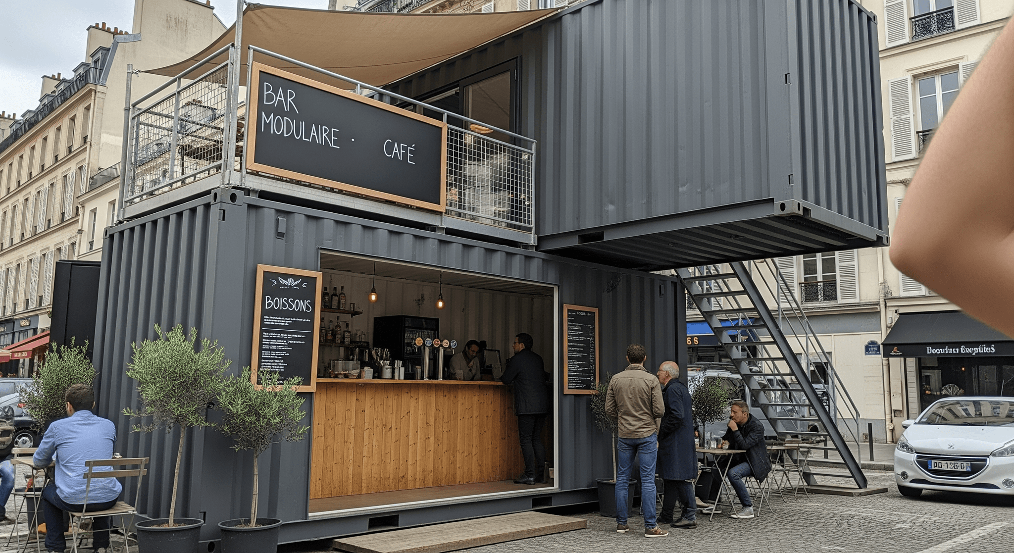Container aménagé bar modulaire MCR sur deux niveaux. Comptoir en bois, terrasse ombragée et espace extérieur.