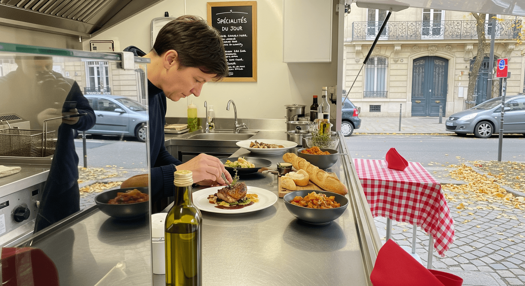 Chef dressant un plat raffiné dans un food truck équipé d'une cuisine professionnelle en inox, prêt pour la restauration mobile.