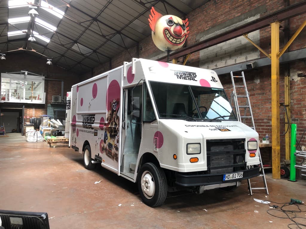 Step van Twisted Metal PlayStation avec tête de clown sur le toit et covering rose vue avant en atelier