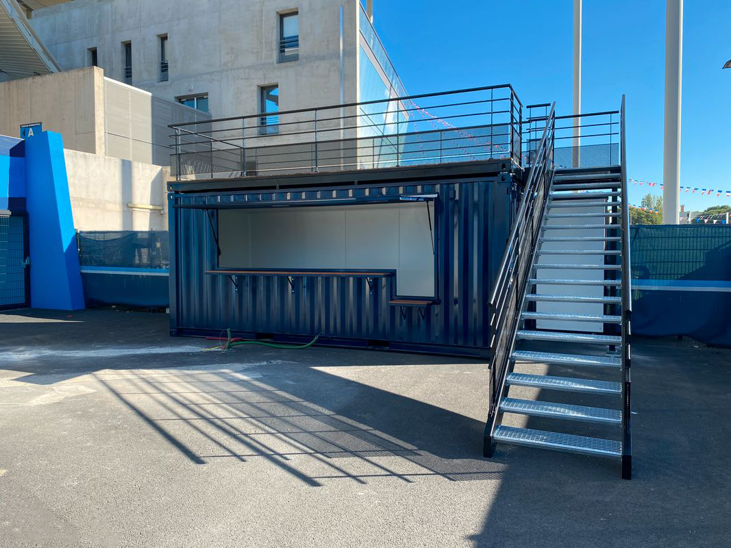 Container bar rooftop bleu avec escalier métallique et terrasse sur le toit