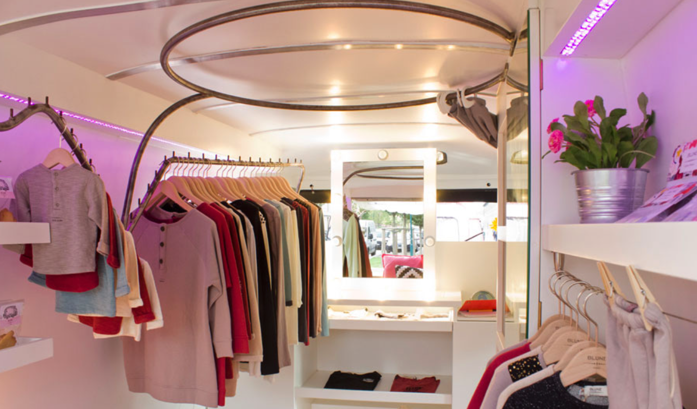 Intérieur du fashion truck Peugeot J9 — penderies, miroir et éclairage LED rose