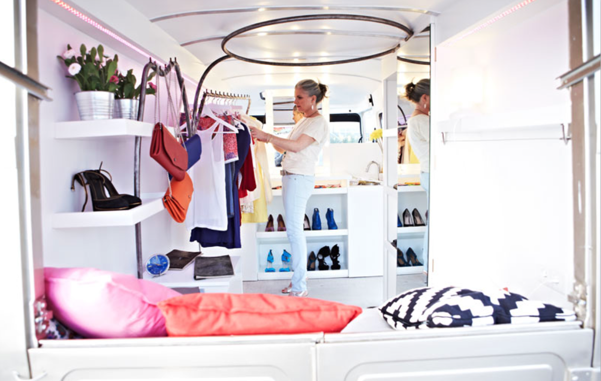 Cliente dans le fashion truck — intérieur avec étagères et penderies